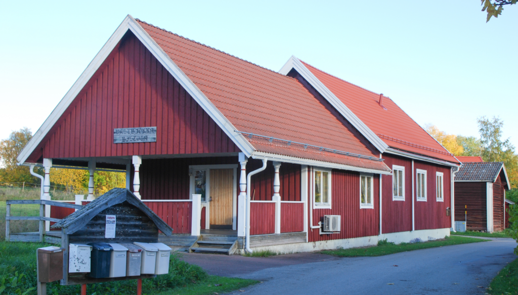 En röd stuga med brevlådor framför.